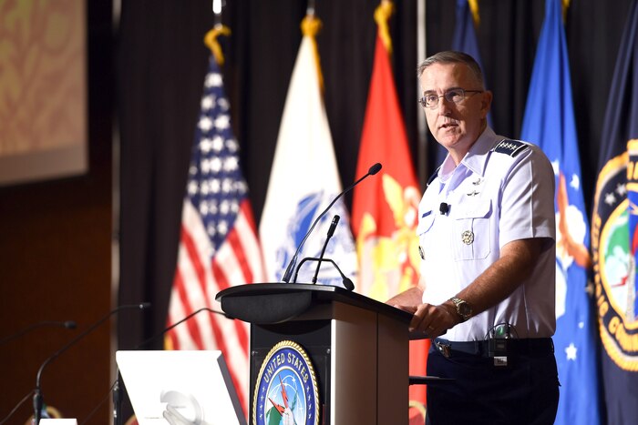 A military commander makes a speech from behind a podium.