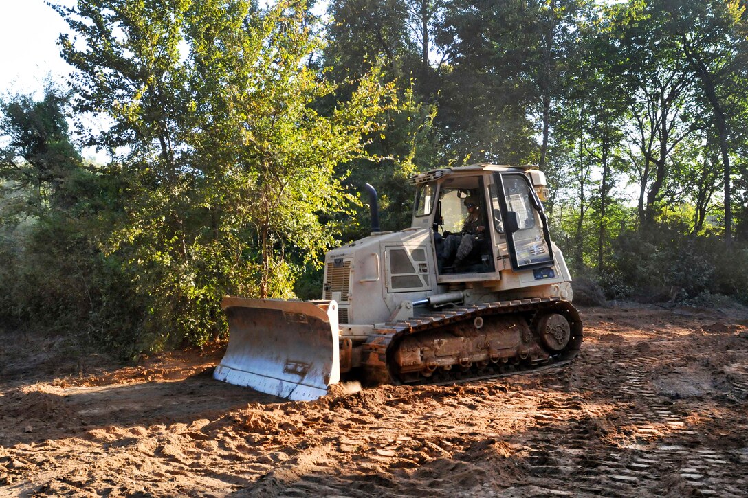 A soldier operates a bulldozer in a base clean-up operation.