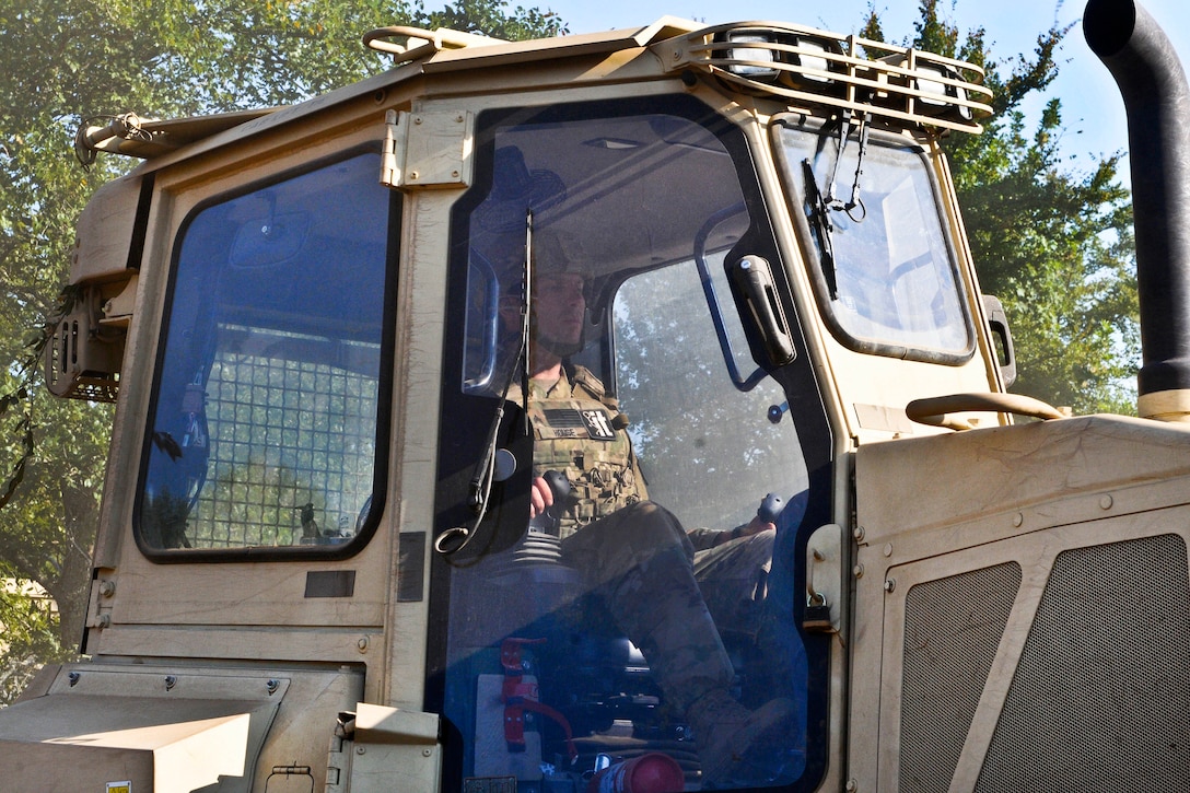 A soldier operates a bulldozer in a base clean-up operation.