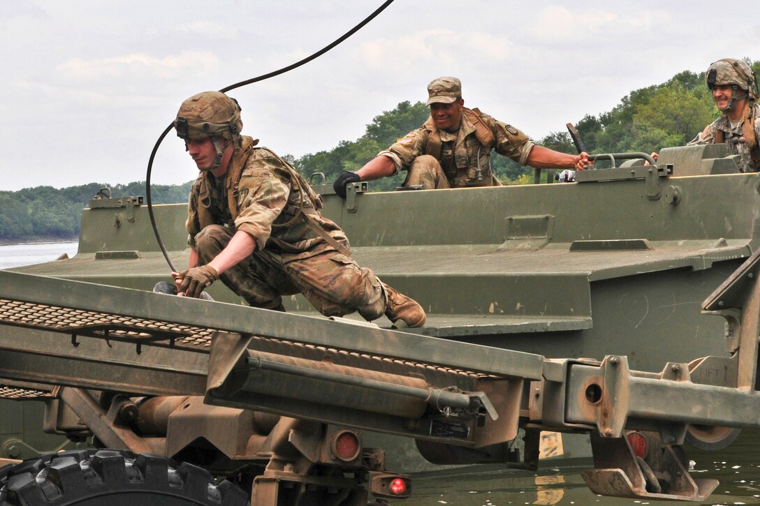 Soldiers prepare to add a section of bridge material to assemble a temporary floating bridge.
