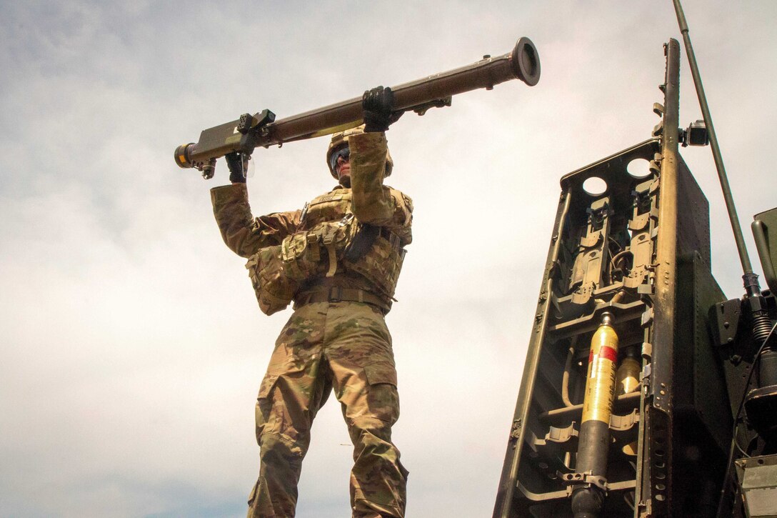A soldier loads a stinger missile onto an Avenger air defense system.