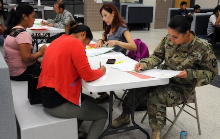 Communities In Schools case manager, Joanne Sanchez, and U.S. Army Reserve Soldier Spc. Launa Bailey, a medical laboratory specialist, complete in-processing with local residents waiting for medical services at Betty Harwell Middle School in Edinburg, Texas. Approximately 50 U.S. Army Reserve Soldiers assigned to the 7235th Medical Support Unit out of Orlando, Texas, worked in partnership with the Texas A&M Colonias program June 16-27 to provide medical care to Hidalgo County's underserved colonia population. Services provided by military personnel are done through the Department of Defense's Innovative Readiness Training, a civil-military program that builds mutually beneficial partnerships between U.S. communities and the DoD. The missions selected meet training & readiness requirements for Army Reserve service members while integrating them as a joint and whole-of-society team to serve our American citizens.