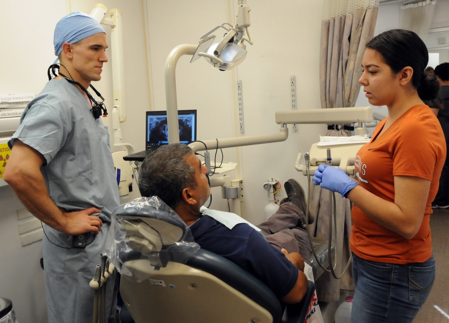 Capt. Matthew Ticich (left), a general dentist assigned to 10th Special Forces Group, and Andrea Betancourt (right), a volunteer from Socorro High School Health Professions Academy, assist a patient during a dental screening at Escontrias Early Childhood Center in Socorro, Texas. Ticich is one of approximately 50 U.S. Army Reserve and U.S. Army Soldiers who are working in partnership with the Texas A&M Colonias program to provide medical care to El Paso County's underserved colonias population. Services provided by military personnel are done through the Department of Defense's Innovative Readiness Training, a civil-military program that builds mutually beneficial partnerships between U.S. communities and the DOD. The missions selected meet training and readiness requirements for Army Reserve service members while integrating them as a joint and whole-of-society team to serve our American citizens.