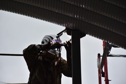 U.S. Army Reserve Staff Sgt. Harold Bevill, a combat engineer with the 317th Engineer Company, out of Homewood, Ill., welds metal sections together on a 4,000 square foot Quonset hut at Joliet Training Area, in Elwood, Ill., as part of a Troop Support Project during Annual Training, July 20.