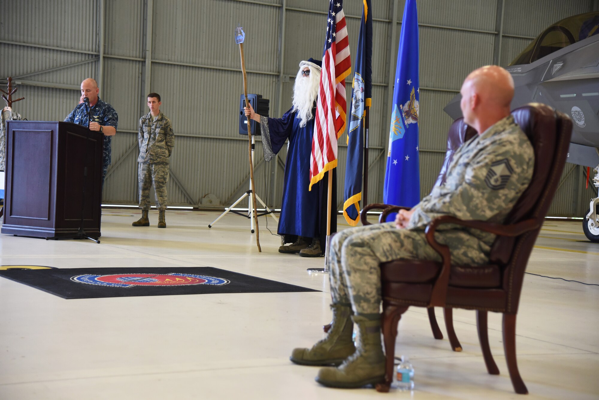 Chief Master Sgt.(select) Matthew Coltrin listens to U.S. Navy Cmdr. Matthew Scott, 33rd Maintenance Squadron commander, address friends and family during his frocking ceremony on Aug. 1, 2018 at Eglin AFB, Fla. A frocking ceremony allows a military member to pin on new rank prior to their promotion date. (U.S. Air Force photo by 1st Lt. Savannah Stephens)