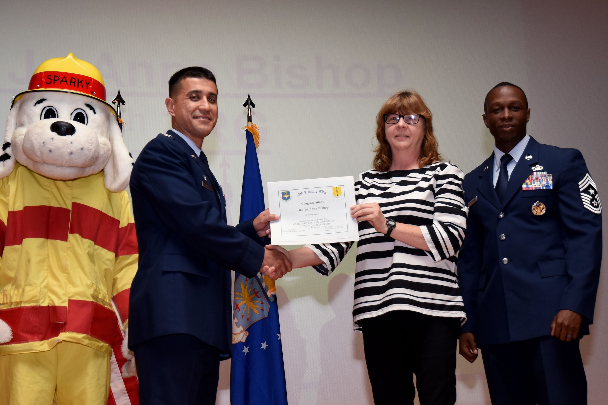 U.S. Air Force Col. Ricky Mills, 17th Training Wing commander, presents the Civilian Supervisory Category III of the Quarter certificate to Jo Anne Bishop, with Chief Master Sgt. Lavor Kirkpatrick, 17th TRW command chief, during the 17th TRW quarterly awards ceremony at the Base Theater on Goodfellow Air Force Base, Texas, July 31, 2018. (U.S. Air Force photo by Airman 1st Class Seraiah Hines/Released)
