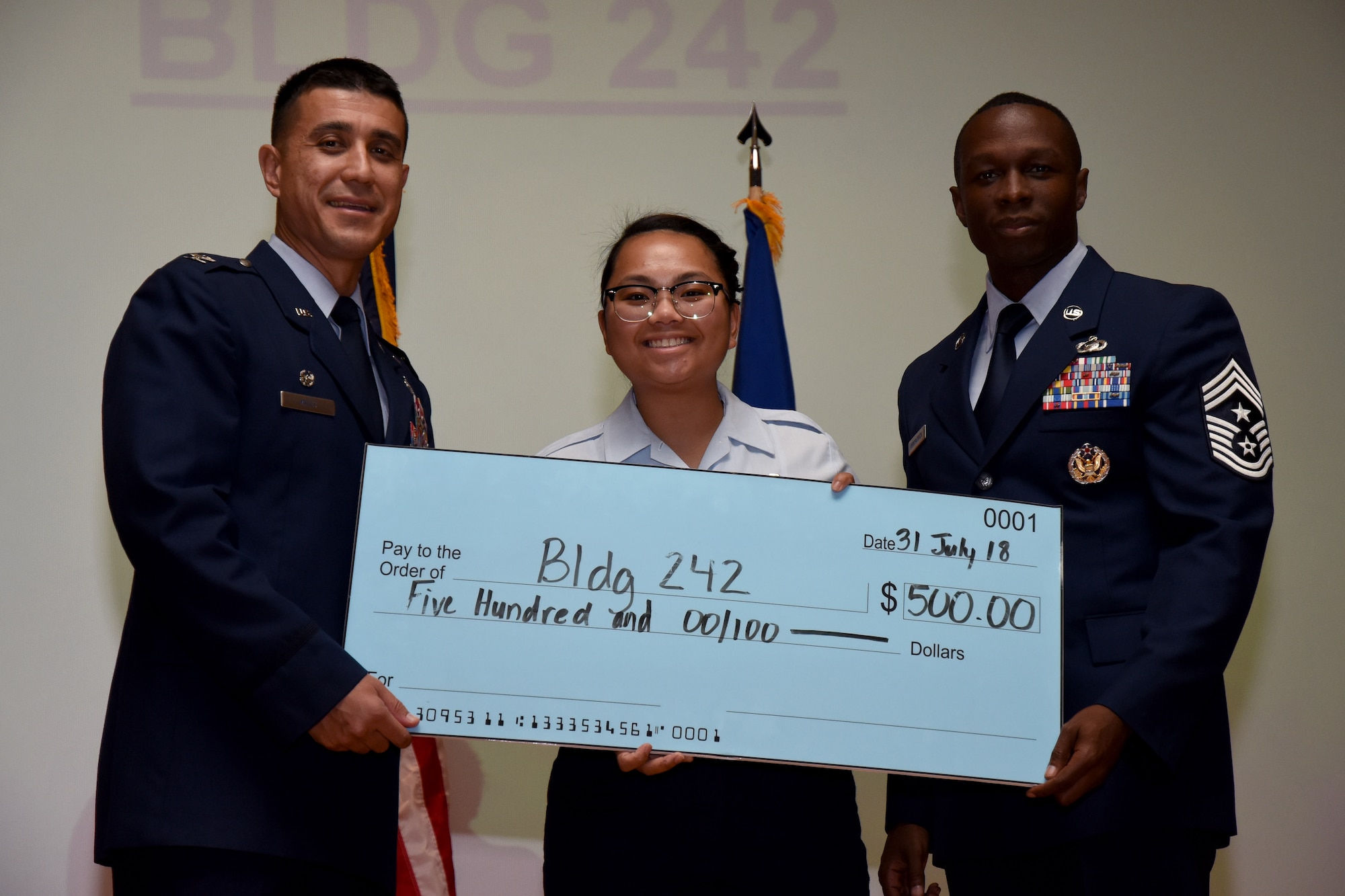 U.S. Air Force Col. Ricky Mills, 17th Training Wing commander, presents a check for the Dormitory of the Quarter to Airman 1st Class Catherine Fajardo, dorm president, on behalf of building 242, with Chief Master Sgt. Lavor Kirkpatrick, 17th TRW command chief, during the 17th TRW quarterly awards ceremony at the Base Theater on Goodfellow Air Force Base, Texas, July 31, 2018. (U.S. Air Force photo by Airman 1st Class Seraiah Hines/Released)