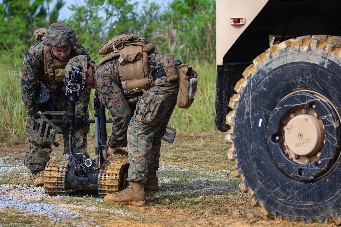 Staff Sgt. David Cain and Sgt. Maximilian Musick lift the tracks of the Mark II Talon explosive ordnance disposal robot during charge employment training Aug. 2, 2018 at Camp Hansen, Okinawa, Japan. The training taught EOD technicians to effectively neutralize IED threats with unmanned robotic platforms, safely finding and removing any hazards. Cain, a native of Fredericksburg, Virginia and Musick, a native of Phoenix, Arizona are EOD technicians with EOD Company, 9th Engineer Support Battalion, 3rd Marine Logistics Group. (U.S. Marine Corps photo by Pfc. Terry Wong)