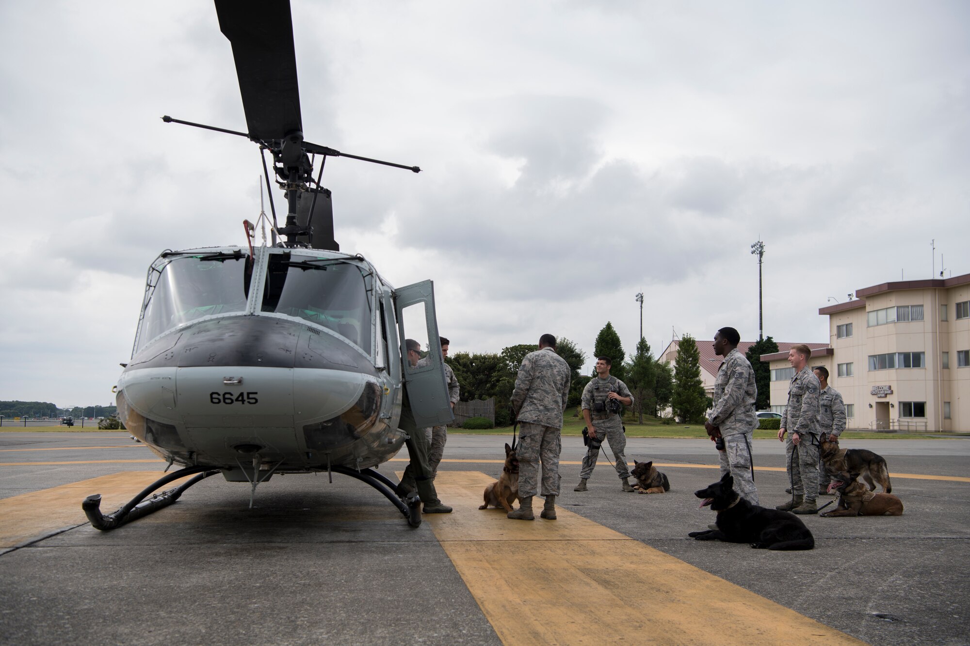 Members of the 374th Security Forces Squadron military working dog section listen to a safety briefing from Tech. Sgt. Dustin Sheffield, 459th Airlift Squadron UH-1N special mission aviator, prior to MWD familiarization flight July 26, 2018, at Yokota Air Base, Japan.