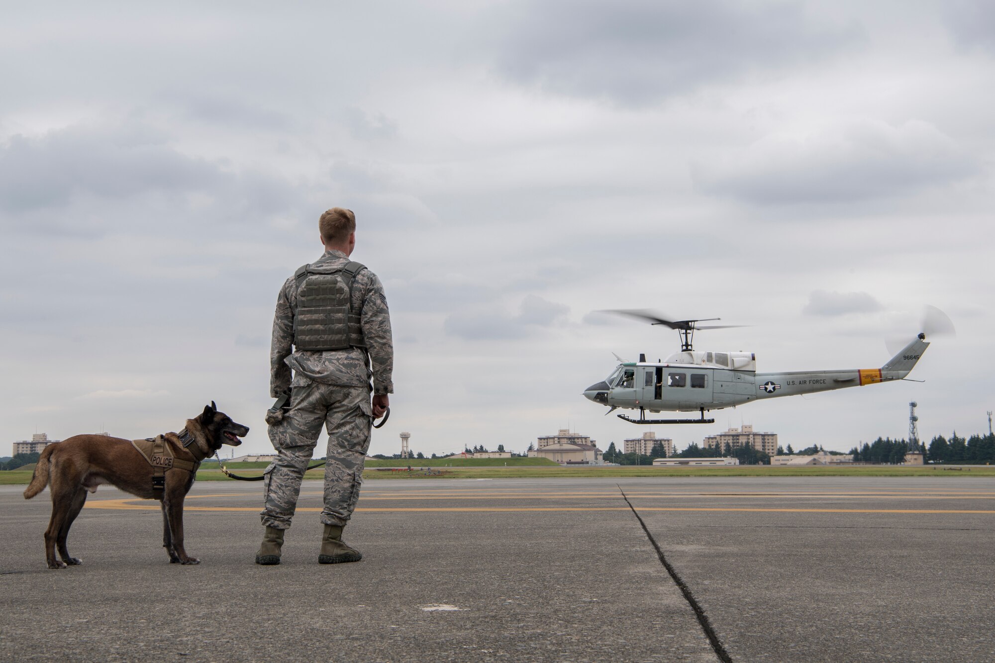 Staff Sgt. Cody Nickell, 374th Security Forces Squadron military working dog handler, watches with Topa, 374 SFS MWD, as a UH-1N helicopter takes off during a 459th Airlift Squadron MWD familiarization flight July 26, 2018, at Yokota Air Base, Japan.