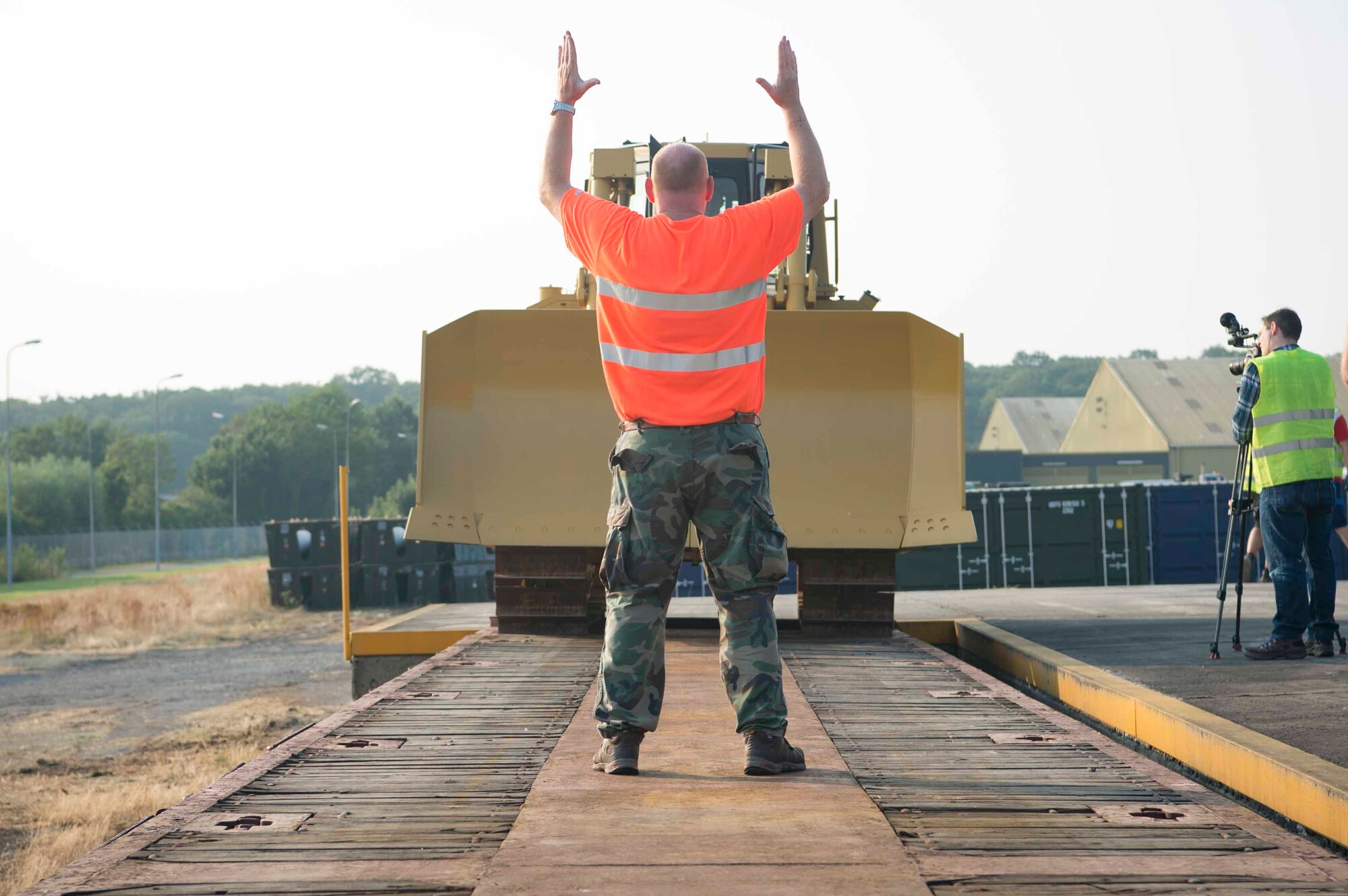 A Warehouse Service Agency employee directs a front loader operator onto a train car in Sanem, Luxembourg, July 23, 2018. The loading was part of an exercise in which a variety of vehicles and equipment, along with an estimated 55 U.S. Air Force and Army personnel, deployed to Krzesiny Air Base, Poland, to test their ability to rapidly set up a fully functional air base in an austere environment. (U.S. Air Force photo by Senior Airman Elizabeth Baker)