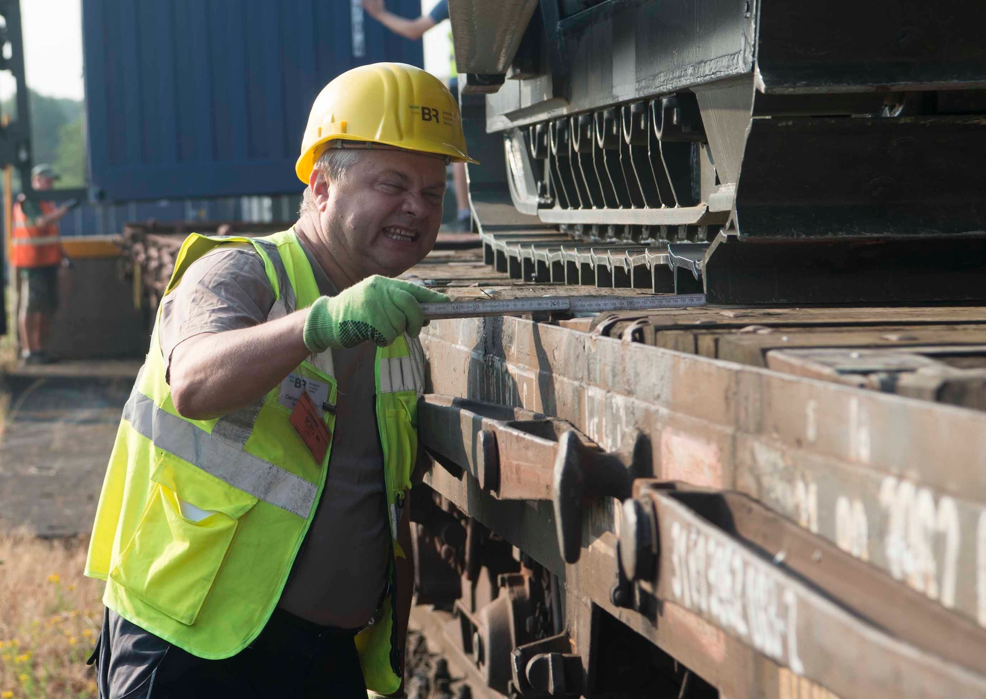 A BR International Consulting Services blocking and bracing specialist measures the space between a front loader and the edge of a train car in Sanem, Luxembourg, July 23, 2018. BR-ICS and Warehouse Services Agency personnel ensured that a variety of vehicles and equipment were properly loaded and secured on train cars bound for Krzesiny Air Base, Poland. (U.S. Air Force photo by Senior Airman Elizabeth Baker)