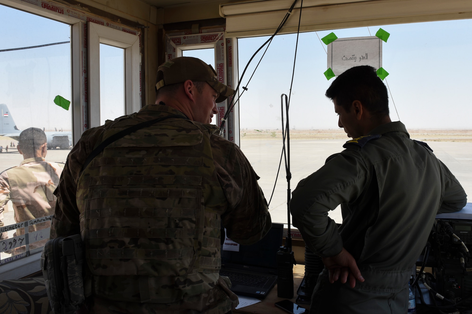 Senior Airman Timothy Feik, a 447th Air Expeditionary Group air traffic controller, advises an Iraqi Air Force controller July 19, 2018, at Qayyarah Airfield West, Iraq. The air traffic controllers at Q-West are a-part of the train, advise and assist mission with the Iraqi Air Force. (U.S. Air Force photo by Tech. Sgt. Caleb Pierce)