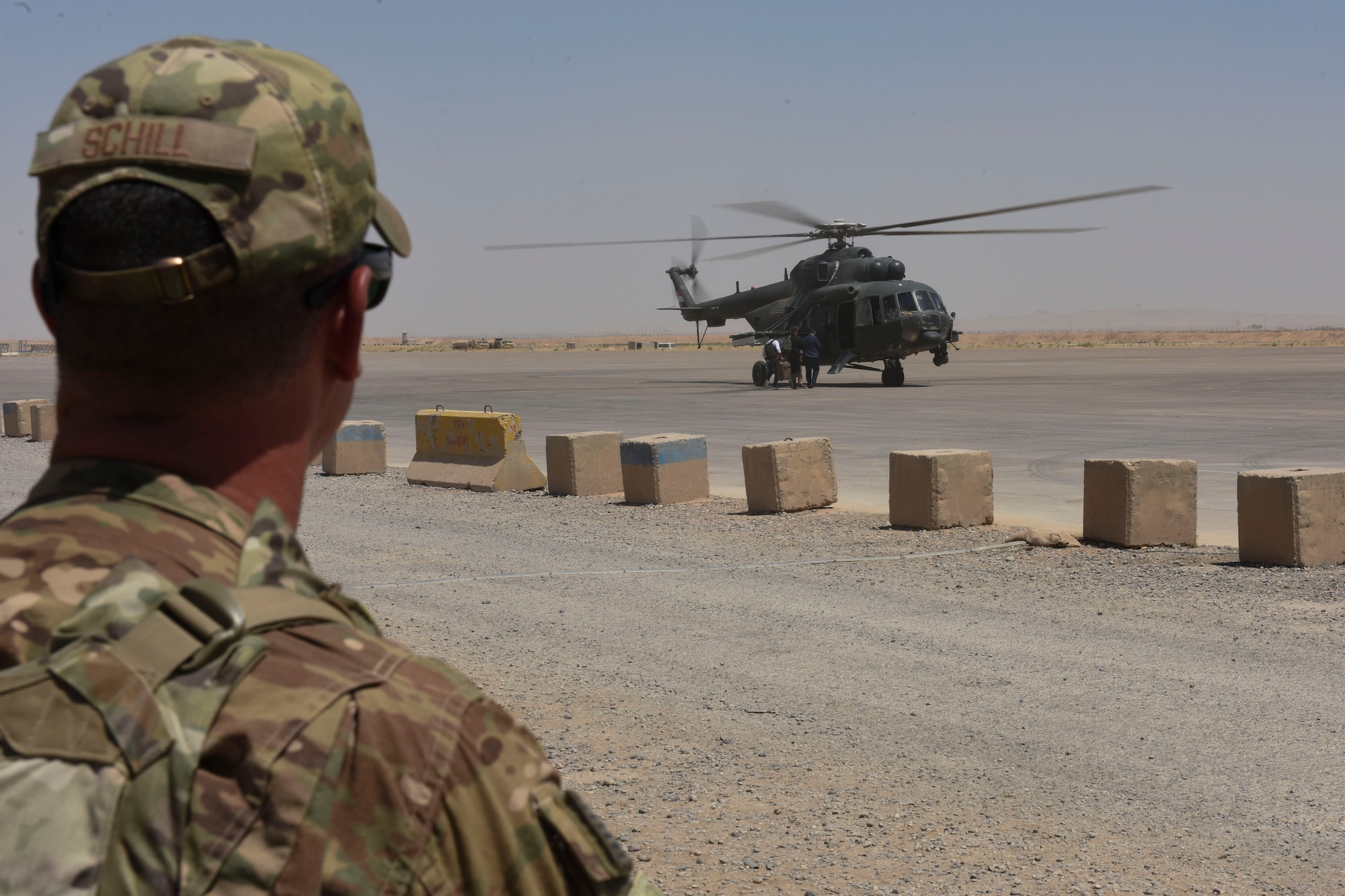 Senior Master Sgt. Adam Schill, 447th Air Expeditionary Group Detachment 1 superintendent, watches people board an Iraqi Air Force helicopter July 19, 2018, at Qayyarah Airfield West, Iraq. The air traffic controllers assigned to the 447th AEG, assist Iraqi Air Force controllers with various types of aircraft movement at the airfield. (U.S. Air Force photo by Tech. Sgt. Caleb Pierce)