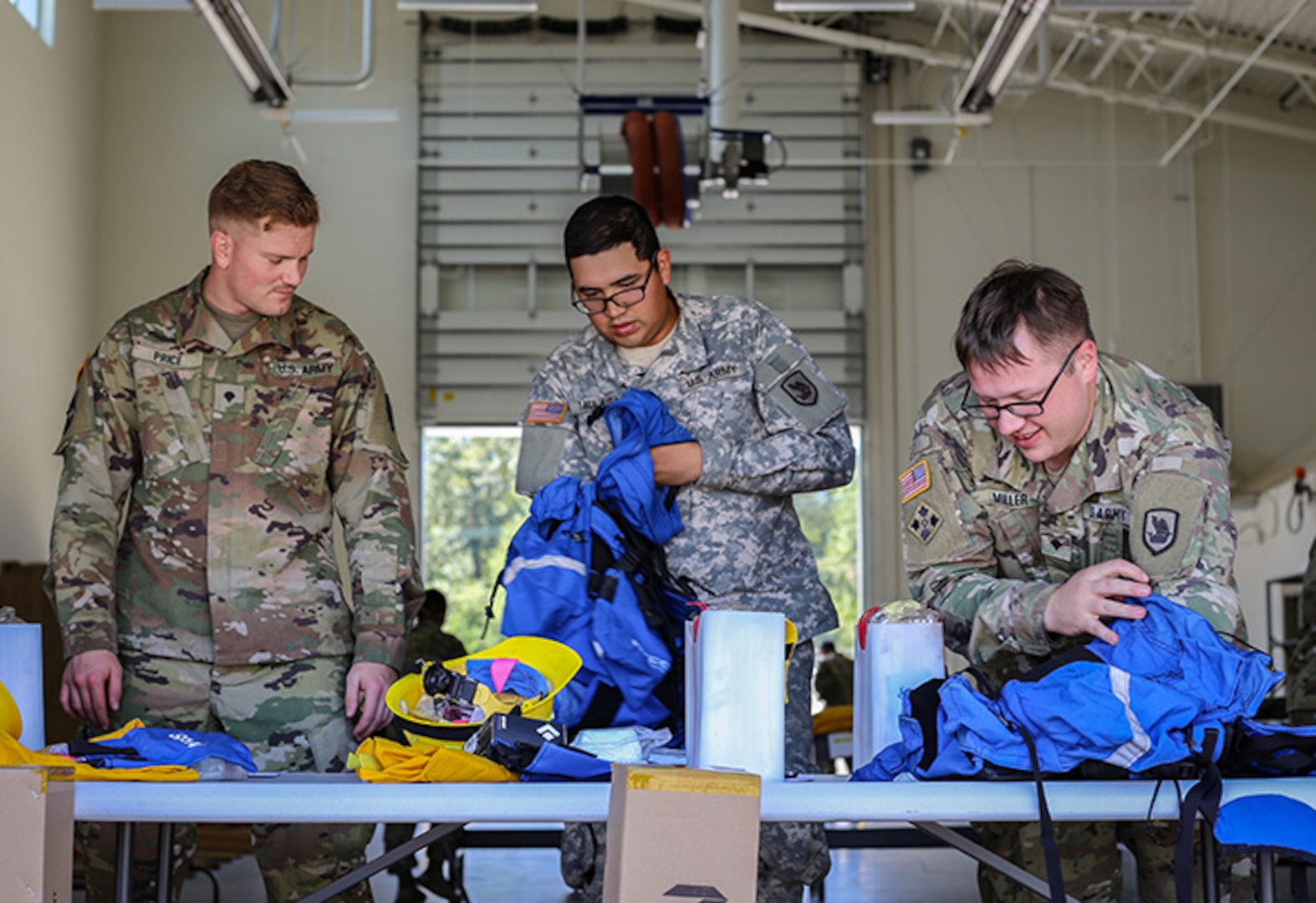 Spec. Derek Price, Pfc. Joshua Taulaga and Spec. Austin Miller with the 176th Engineer Company inventory the new equipment they received prior to going to help fight wildfires impacting Eastern Washington, Aug. 1, 2018, at Camp Murray, Washington.
