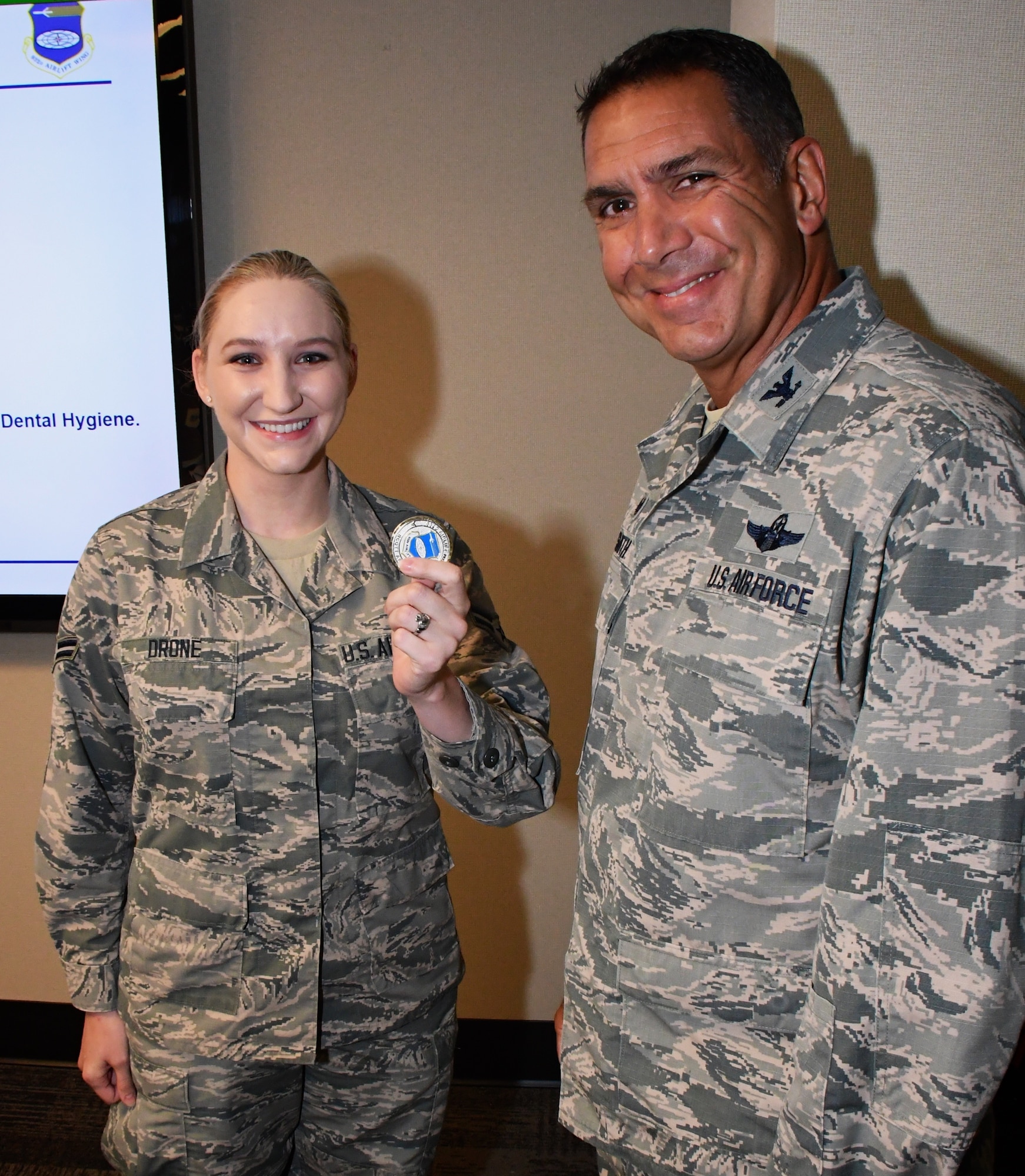 At right, the commander of the 932nd Airlift Wing, Col. Raymond Smith, presented a special wing coin to Airman First Class Megan Drone, who was spotlighted during the pre-Unit Training Assembly meeting on August 3, 2018, at Scott Air Force Base.   Airman Drone is a health service management specialist in the 932d Medical Group's 932nd Medical Squadron.  She said, "I enjoy experiencing being in the military part time, while continuing my civilian career and family life, and having control of that balance while meeting so many wonderful people."  (U.S. Air Force photo by Lt. Col. Stan Paregien