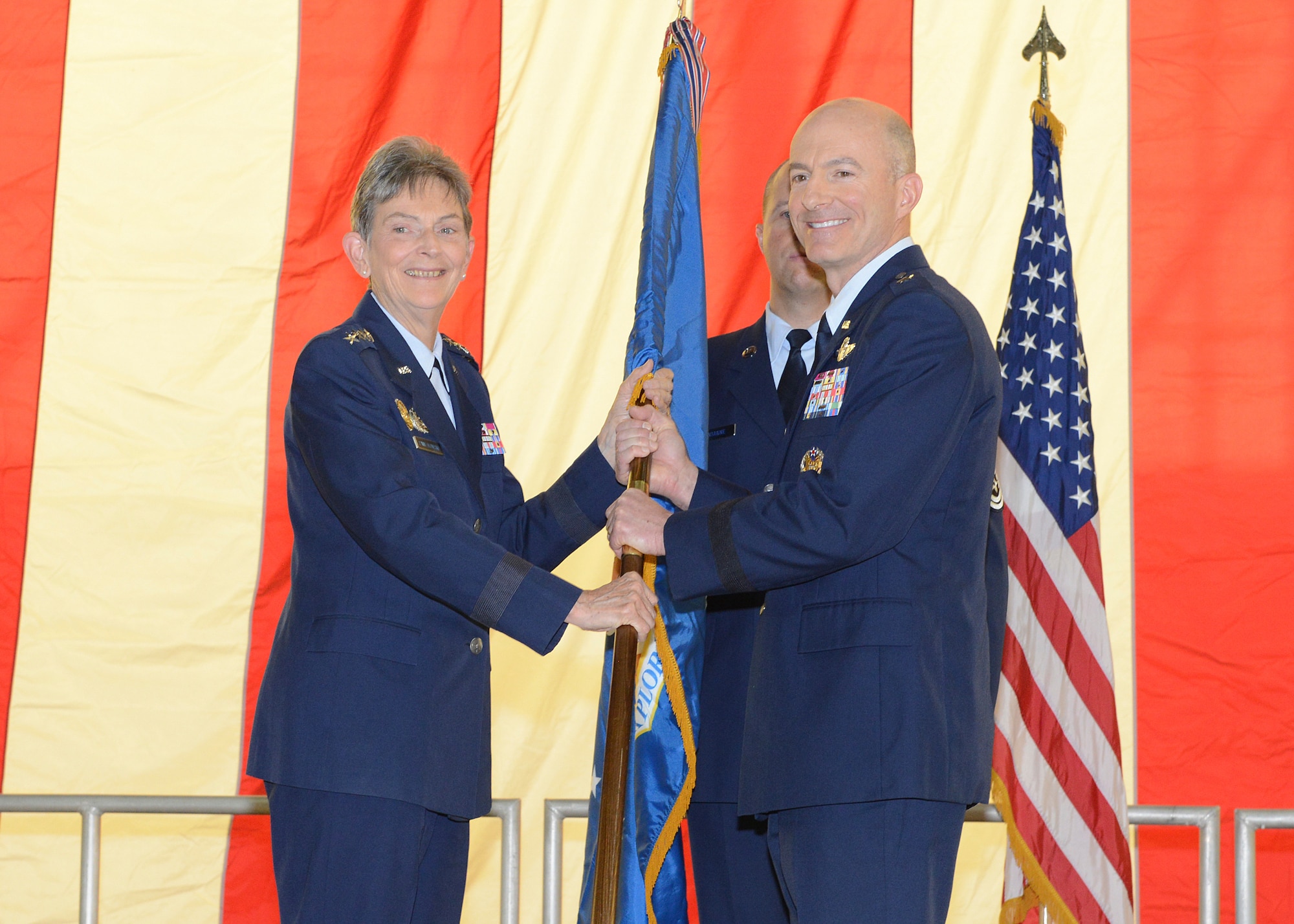 Brig. Gen. Christopher P. Azzano poses with the Air Force Test Center guidon with the commander of Air Force Materiel Command, Gen. Ellen Pawlikowski, during a change-of-command held in Hangar 1600 at Edwards Air Force Base, Aug. 3. (U.S. Air Force photo by Kenji Thuloweit)