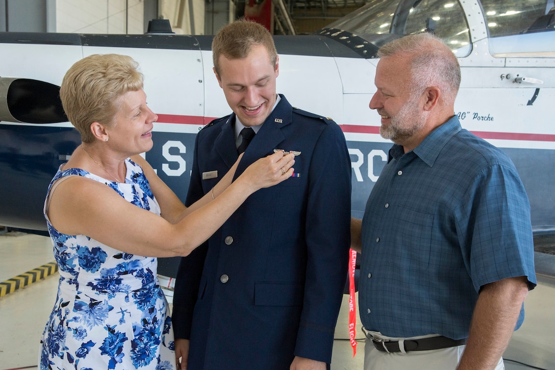The parents of 2nd Lt. Nickolas Brandt, Pilot Training Next student, pin on his aeronautical wings during his graduation August 3, 2018, at the Armed Forces Reserve Center, Austin, Texas. PTN is a program to explore and potentially prototype a training environment that integrates various technologies to produce pilots in an accelerated, cost efficient, learning-focused manner.  (U.S. Air Force photo by Sean M. Worrell)