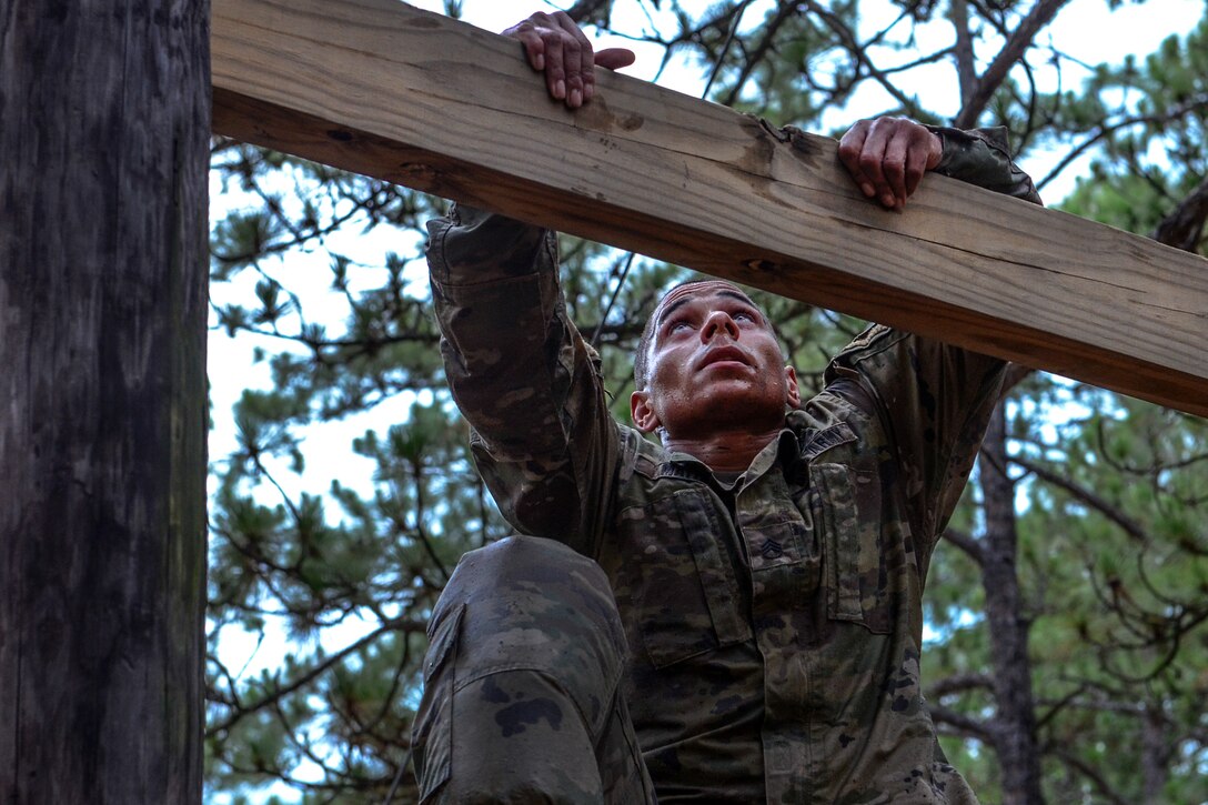A soldier climbs up the high ladder obstacle.