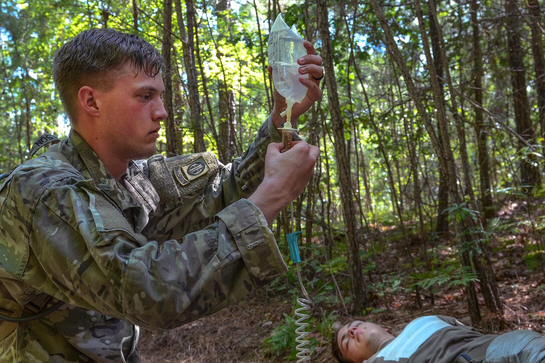 A soldier provides an IV to a role-playing casualty victim.