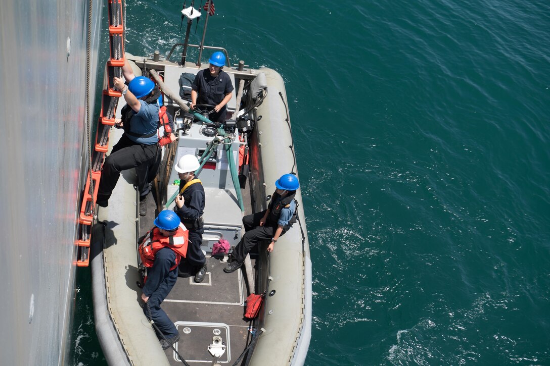 A Canadian sailor climbs down the pilot's ladder to a rigid-hull inflatable boat.