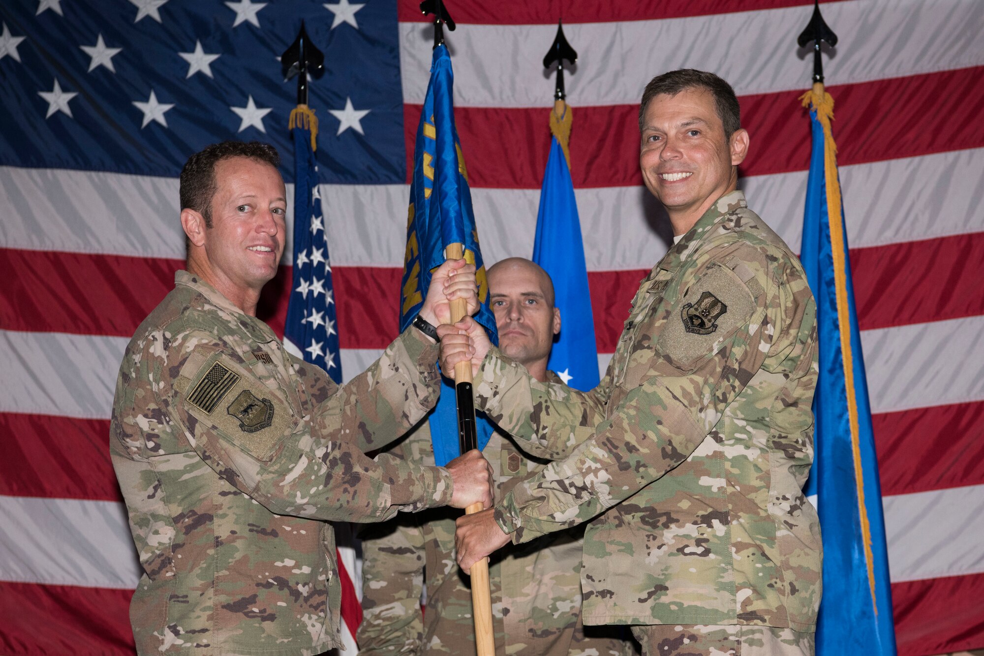 Brig. Gen. David Iverson, 332nd Air Expeditionary Wing commander and presiding officer, gives the 332nd Expeditionary Medical Group guidon to Col. Joseph Dell at a change of command ceremony, Aug. 3, 2018, at an undisclosed location in Southwest Asia.