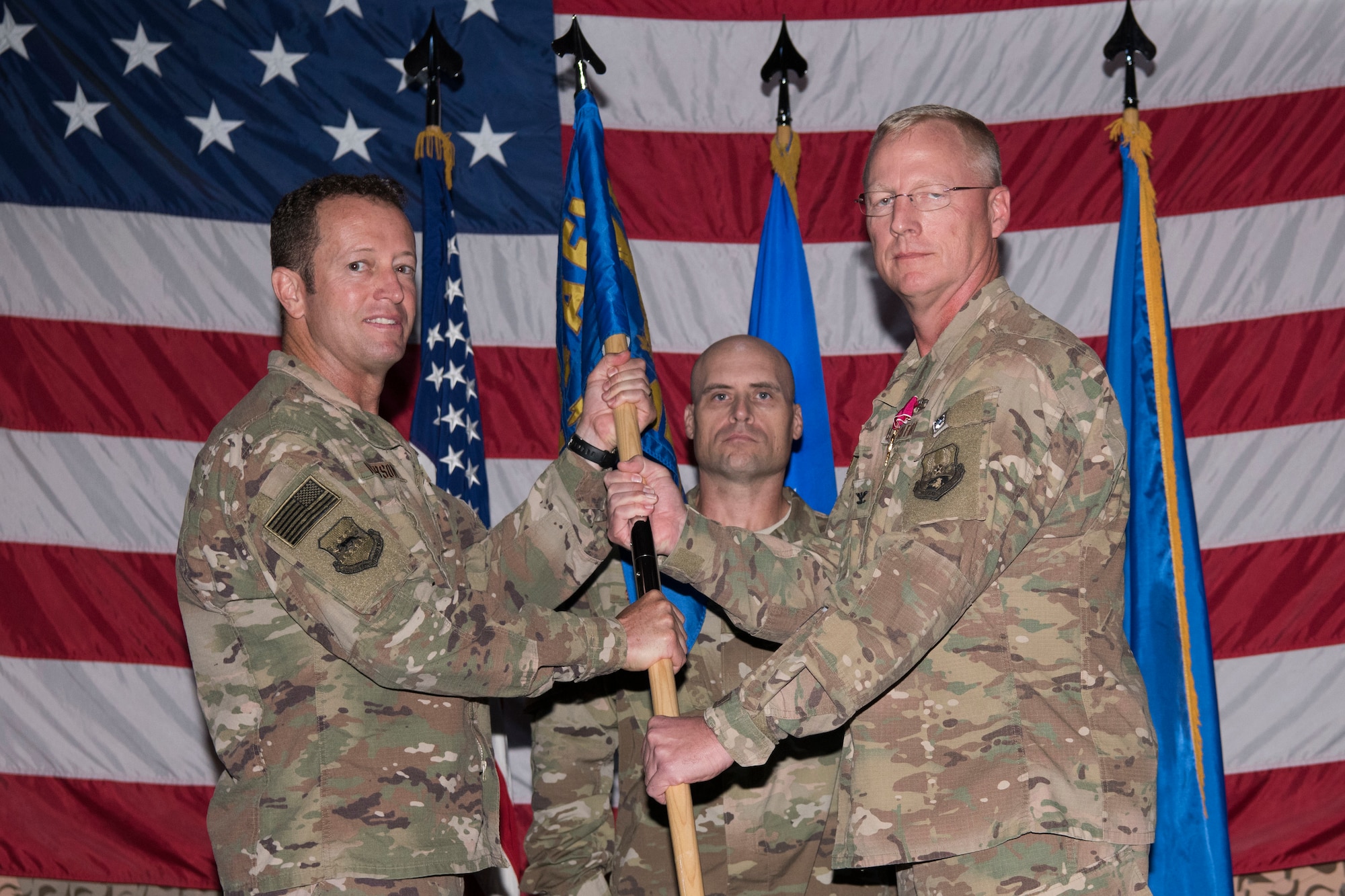 Brig. Gen. David Iverson, 332nd Air Expeditionary Wing commander and presiding officer, takes the 332nd Expeditionary Medical Group guidon from Col. Bradley Nielsen at a change of command ceremony, Aug. 3, 2018, at an undisclosed location in Southwest Asia.