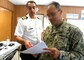 Military leaders converse while looking at a computer screen.