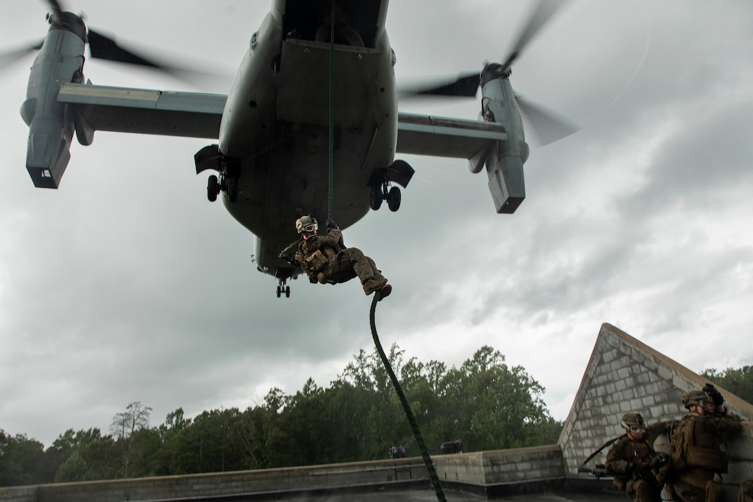 A Marine with Battalion Landing Team, 1st Battalion, 2nd Marines, 22nd Marine Expeditionary Unit fast ropes out of an MV-22 Osprey during the 22nd MEU Deployment for Training at Fort A.P. Hill, VA., July 31, 2018. In preparation for their upcoming deployment, the Marines practiced embassy reinforcement by fast roping onto a rooftop and clearing out a simulated embassy building, which in turn allowed the Marines to train in an urban environment.