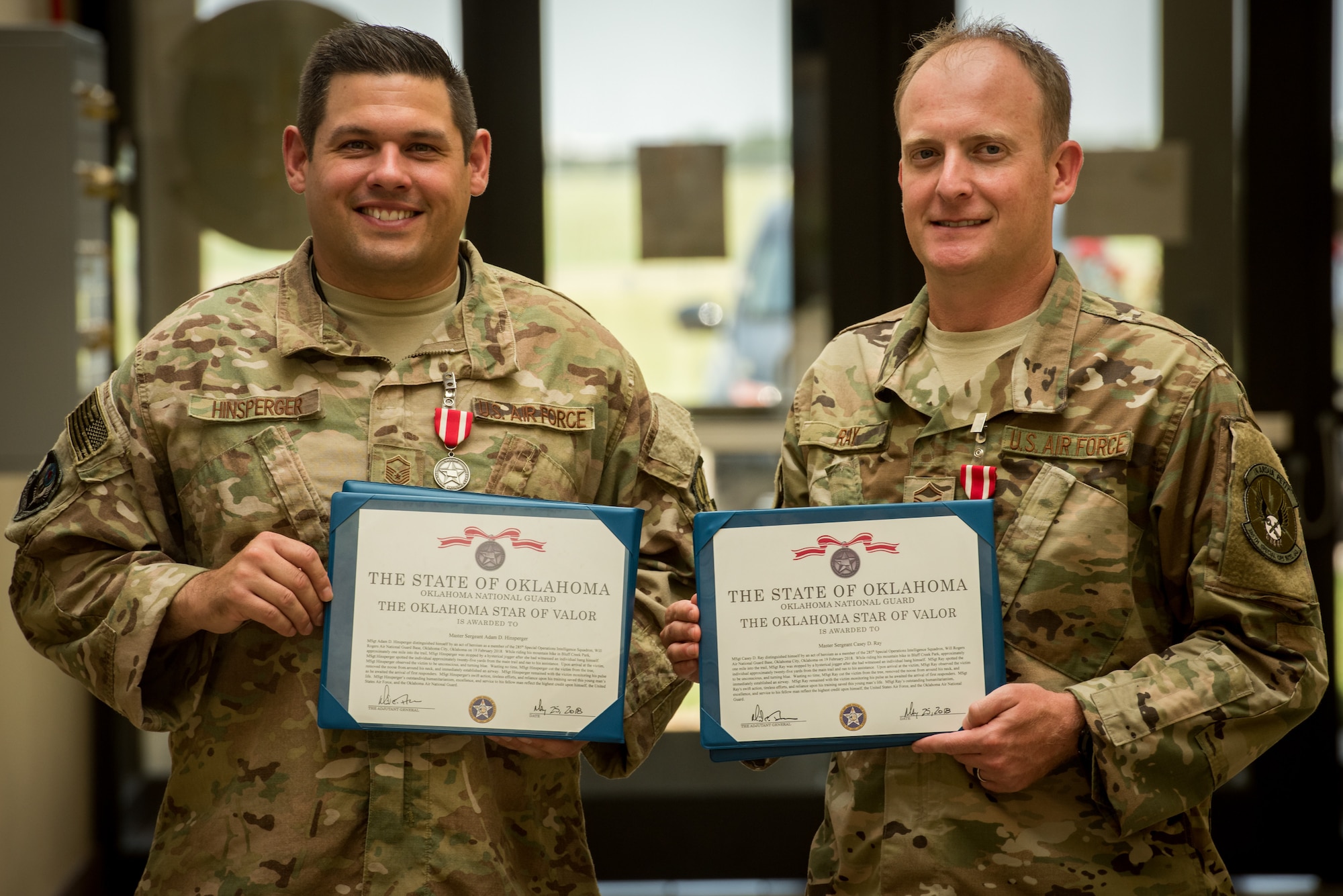 Master Sgt. Adam Hinsperger (left), 285th Special Operations Intelligence Squadron (SOIS) intelligence analyst, and Master Sgt. Casey Ray (middle), 285th SOIS intelligence analyst, pose with their Star of Valor awards Aug. 4, 2018, at Will Rogers Air National Guard Base, Oklahoma City.