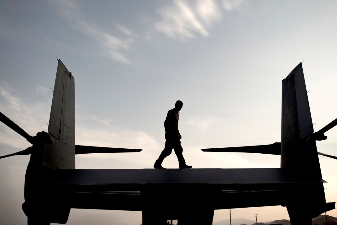 An airman walks on top on an aircraft.