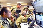 Soldiers gather around computers.