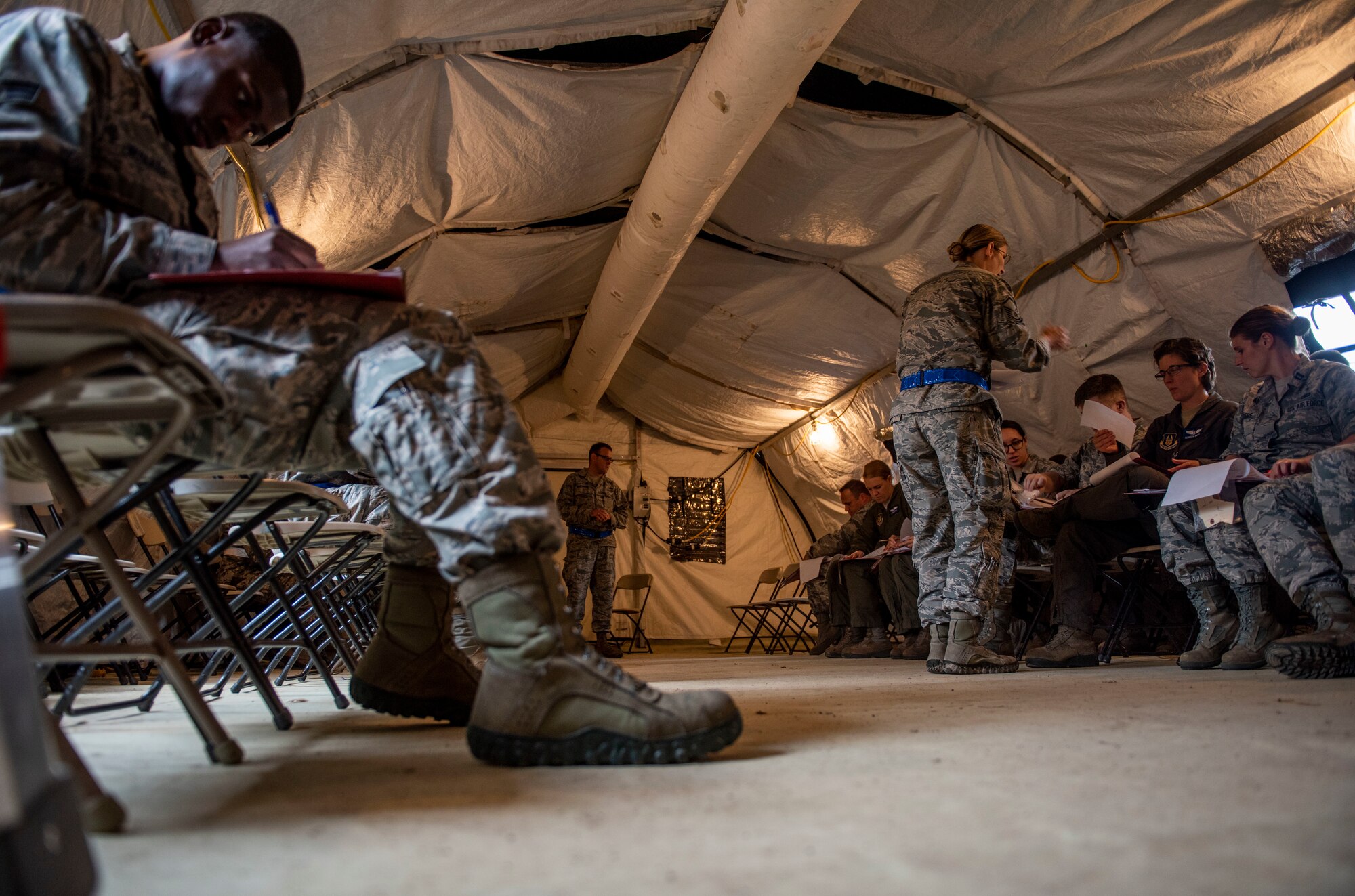 Airmen fill out in-processing paperwork at the beginning of a base exercise, July 31, 2018, at Scott Air Force Base, Illinois. Airmen with the 375th Force Support Squadron were responsible for guiding the exercise players through the paperwork process. (U.S. Air Force photo by Airman 1st Class Tara Stetler)