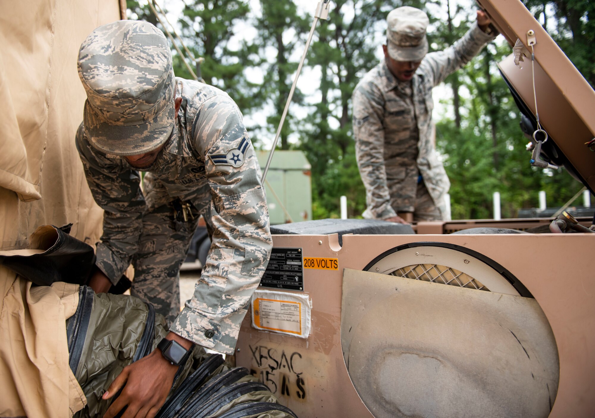 Airman 1st Class Joshua Allen and Airman 1st Class Javon Davidson, 375th Civil Engineer Squadron HVAC technicians, repair an air conditioning unit during a base exercise, July 31, 2018, at Scott Air Force Base, Illinois. The exercise tested Airmen readiness with simulated chemical attacks. (U.S. Air Force photo by Airman 1st Class Tara Stetler)