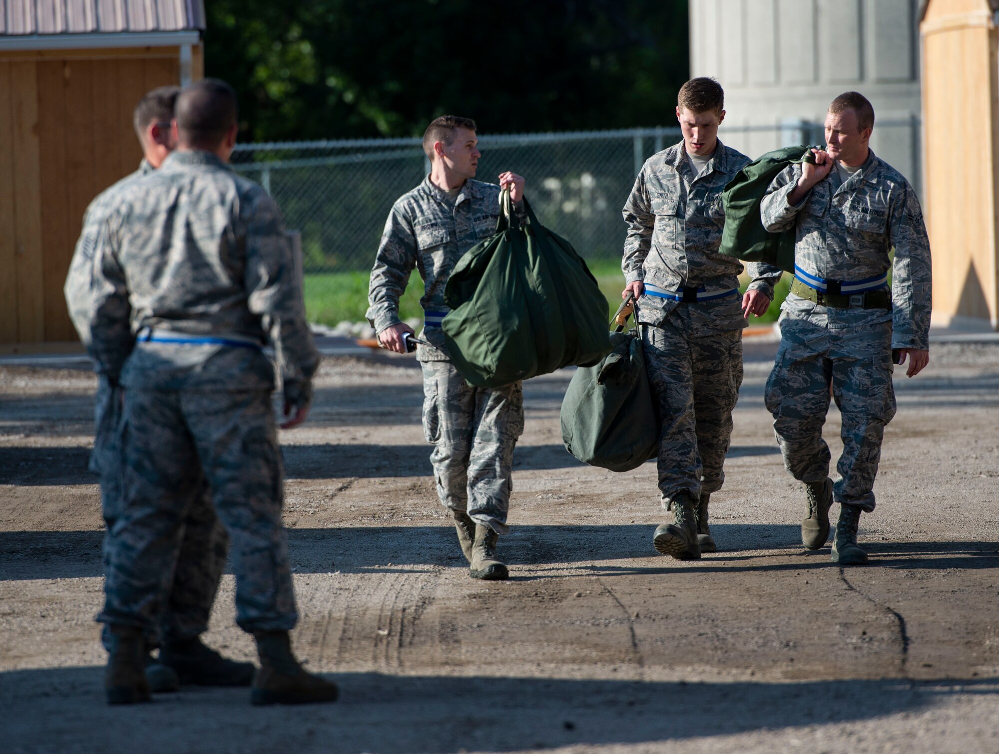 Airmen carry their gear to their tent during a base exercise, Aug. 1, 2018, at Scott Air Force Base, Illinois. The two-phase exercise lasted five days and tested Airmen’s ability to respond to explosions and chemical attacks. (U.S. Air Force photo by Airman 1st Class Tara Stetler)