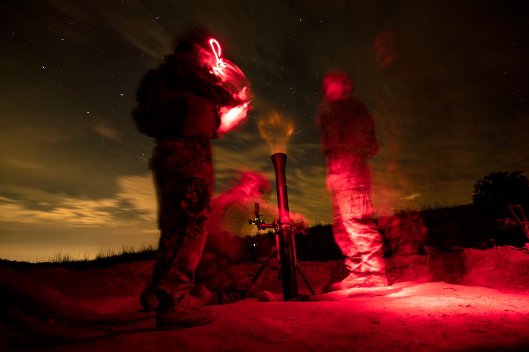 Marines fire a mortar at night.