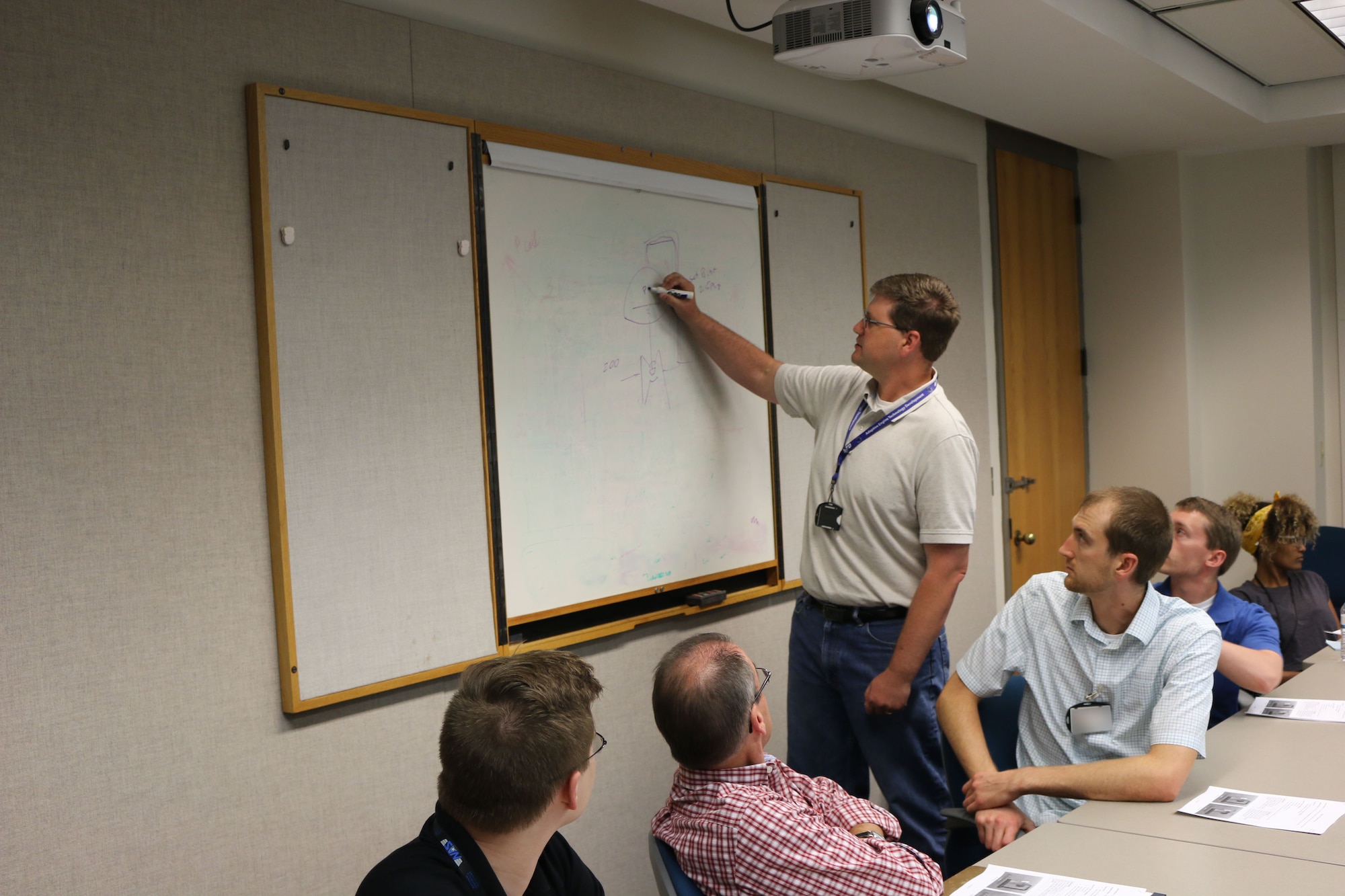Austin Voorhes (standing), a senior mechanical design engineer at Arnold Air Force Base, discusses steam regulators during a lunch and learn session in the Carroll Building on July 25. Voorhes was recently recognized for establishing the lunch and learns at Arnold. More than 100 lunch and learns have been held since Voorhes began the effort a little more than three years ago. (U.S. Air Force photo by Bradley Hicks) (This image was manipulated by obscuring badges for security purposes)