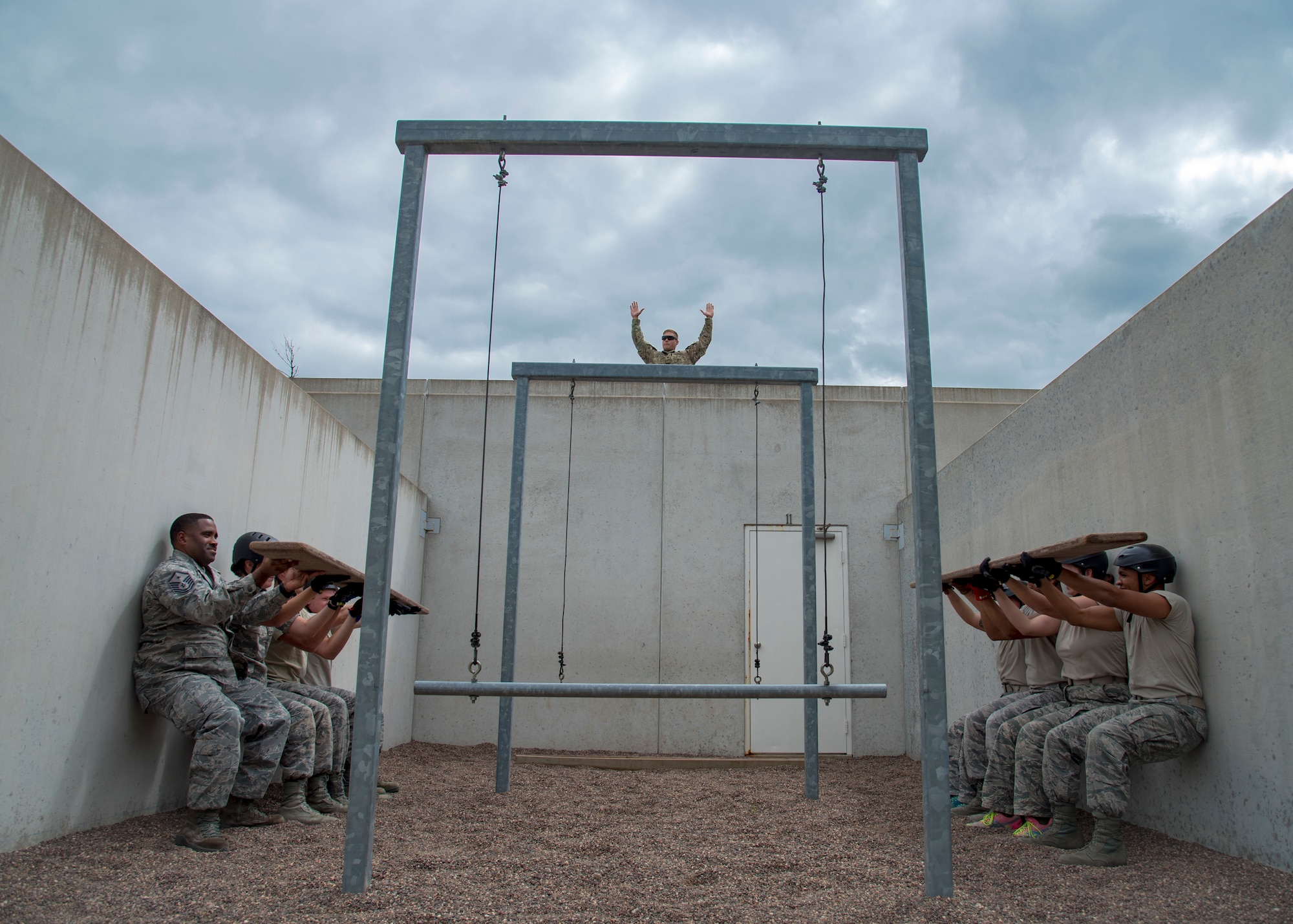 U.S. Army Specialist Zachary Lichucki, the leadership development course leader at Volk Field Air National Guard Base, Wisconsin, encourages Airmen while they perform wall sits after incorrectly completing a section of the course July 26, 2018. The Airmen were participants of the 2018 Junior Enlisted Orientation Program which allows junior enlisted Airmen to better understand the mission of all the units in the Wisconsin Air National Guard. 
(U.S. Air National Guard photo by Airman Cameron Lewis)