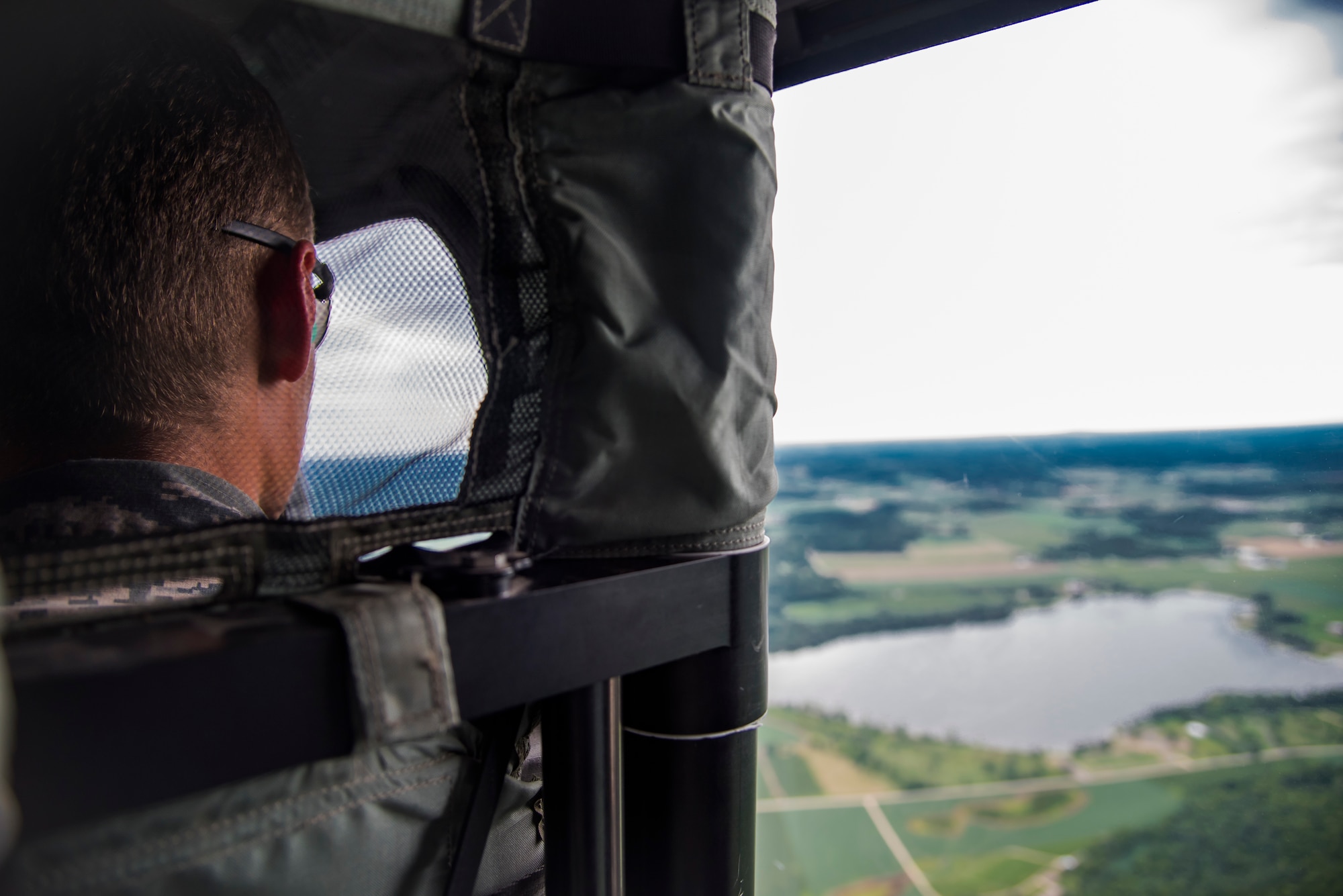 Airman 1st Class Silas Westrick, a security forces member with the 115th Fighter Wing, Truax Field, Wisconsin, looks out the window of a UH-60 Black Hawk helicopter while in flight from Truax Field to Volk Field July 25, 2018. Westrick was a participant of the 2018 Junior Enlisted Orientation Program which allows junior enlisted Airmen to better understand the mission of all the units in the Wisconsin Air National Guard. 
(U.S. Air National Guard photo by Airman Cameron Lewis)