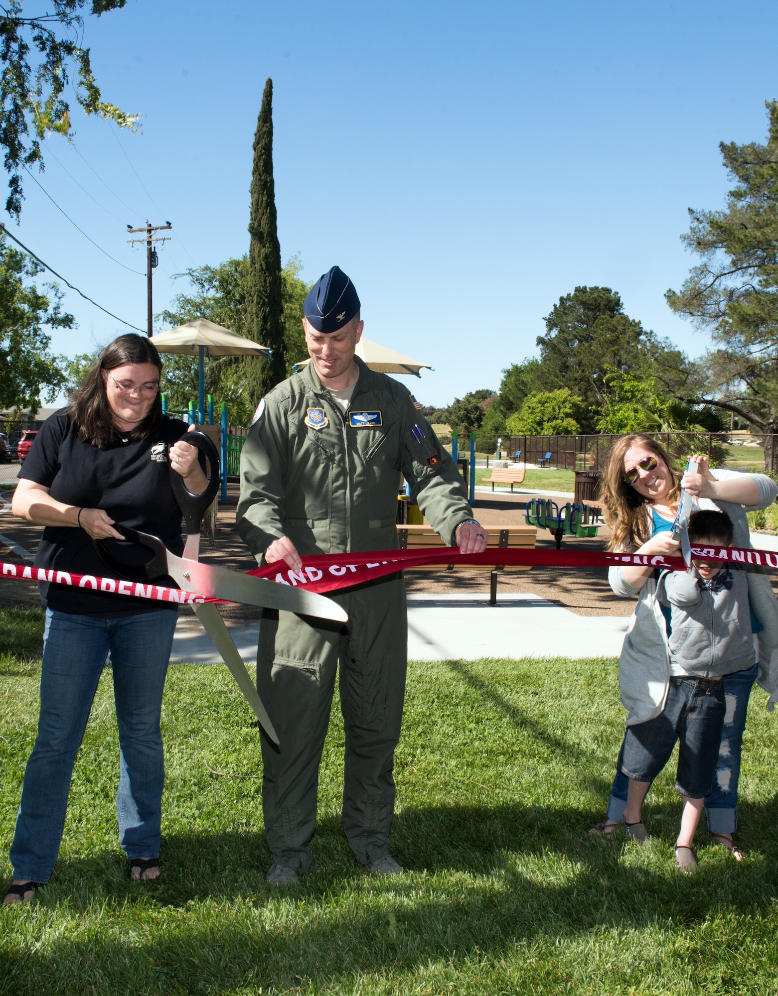 Col. Matthew Leard, center, 60th Air Mobility Wing vice commander, helps cut a ribbon for a new park with Vanessa Pearson, left, and Bendle Bell, right, at Travis Air Force Base, Calif., May 11, 2018. “The Inclusive Park” was an 18-month project and is designed for all abilities with emphasis on military families with special needs. (U.S. Air Force photo by Louis Briscese)
