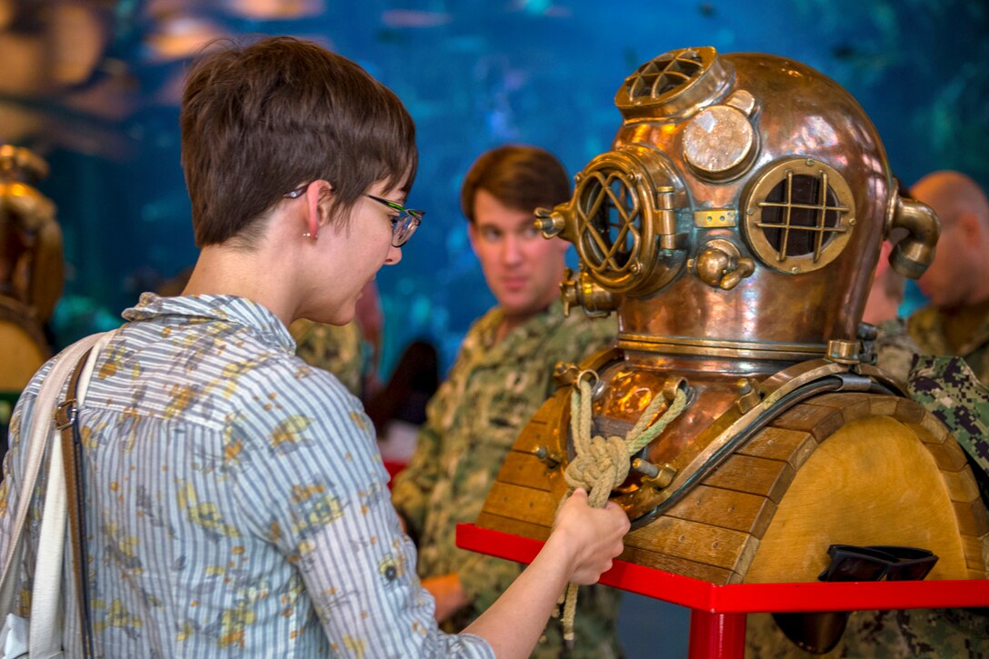 A visitor at the Seattle Aquarium inspects a Navy dive helmet.
