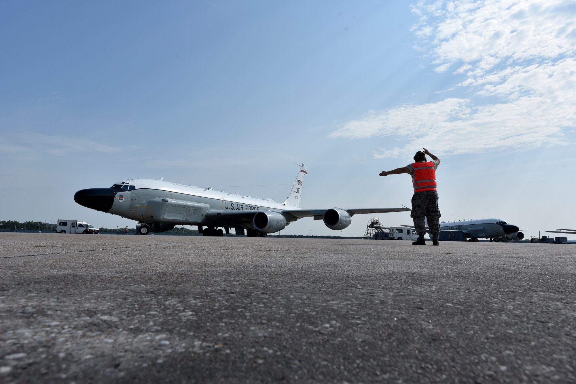 A 55th Aircraft Maintenance Squadron member marshalls a RC-135V/W Rivet Joint from its parking spot  for a weekend training sortie Aug. 5, 2018 at Offutt Air Force Base, Nebraska. The aircraft is an extensively modified C-135. The Rivet Joint's modifications are primarily related to its on-board sensor suite, which allows the mission crew to detect, identify and geolocate signals throughout the electromagnetic spectrum. The mission crew can then forward gathered information in a variety of formats to a wide range of consumers via Rivet Joint's extensive communications suite. (U.S. Air Force photo by 2nd Lt. Drew Nystrom)