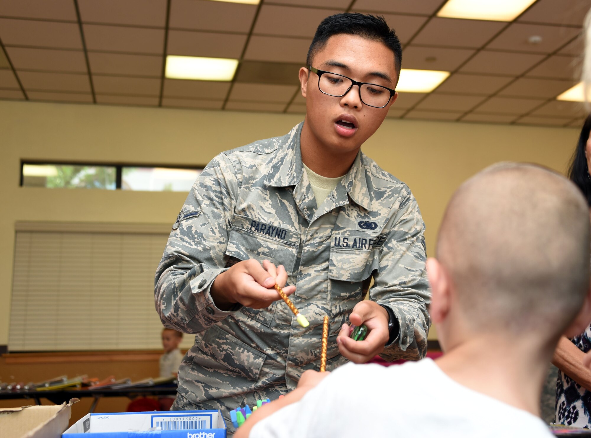 Airman Arnel Parayno, 60th Logistic Readiness Squadron customer service staff member, offers a Travis student a pencil during Operation Homefront’s “Back to School Brigade” Aug. 2 at the base’s First Street Chapel. The event helped to provide children of E-1 to E-6 Airmen with free school supplies for the upcoming academic year. (U.S. Air Force photo by Airman 1st Class Christian Conrad)