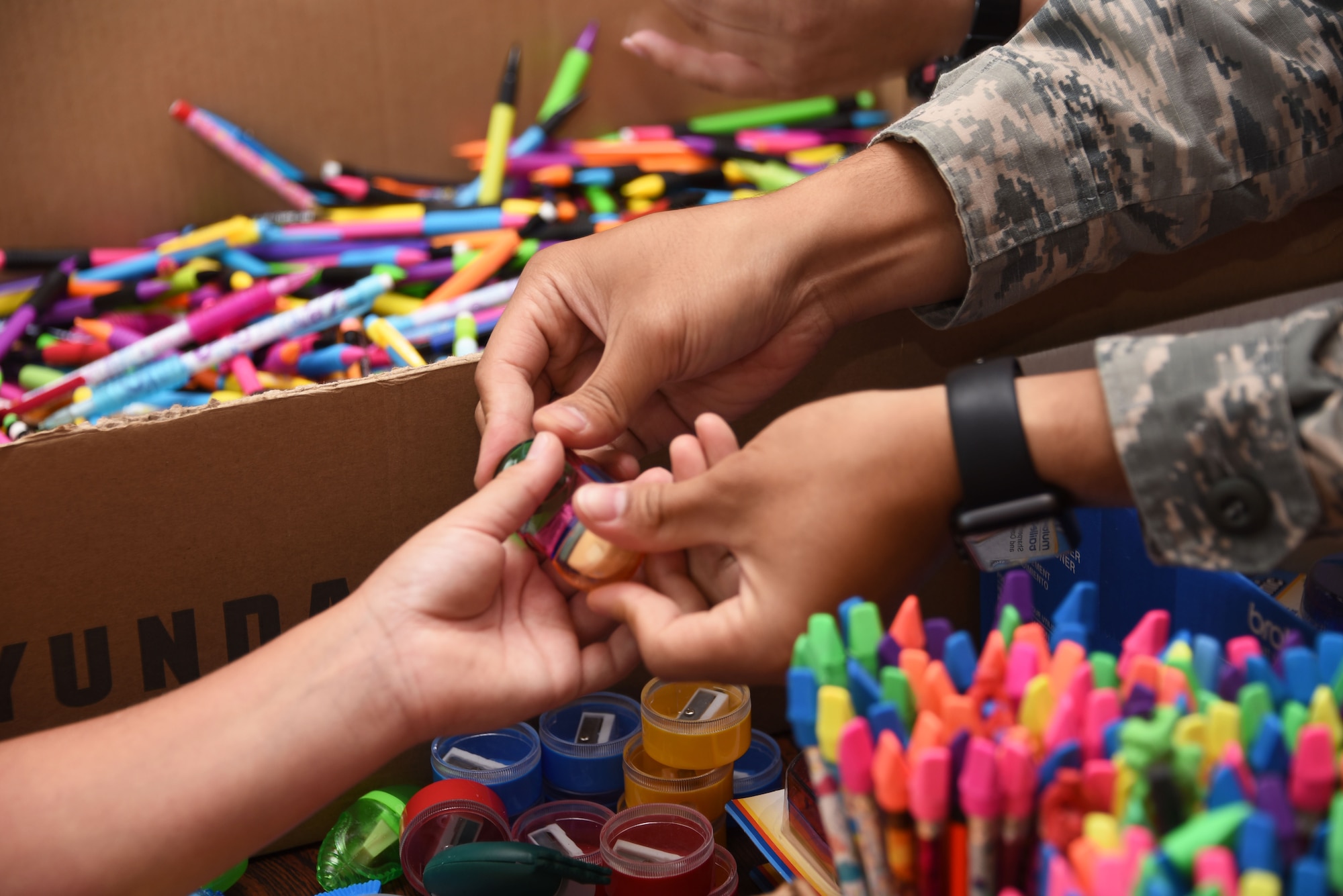 Airman Arnel Parayno, 60th Logistic Readiness Squadron customer service staff member, offers a hand eraser to a Travis student during Operation Homefront’s “Back to School Brigade” Aug. 2 at the base’s First Street Chapel. The event helped to provide children of E-1 to E-6 Airmen with free school supplies for the upcoming academic year. (U.S. Air Force photo by Airman 1st Class Christian Conrad)