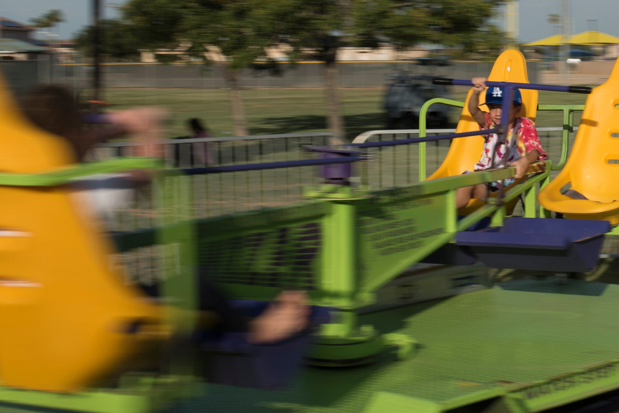 A child holds on tight while on a spinning carnival ride at the Back-To-School Bash July 25, 2018, at Luke Air Force Base, Ariz. The Bash offered families and attendees free food, games, and prize drawings. (U.S. Air Force photo by Senior Airman Ridge Shan)