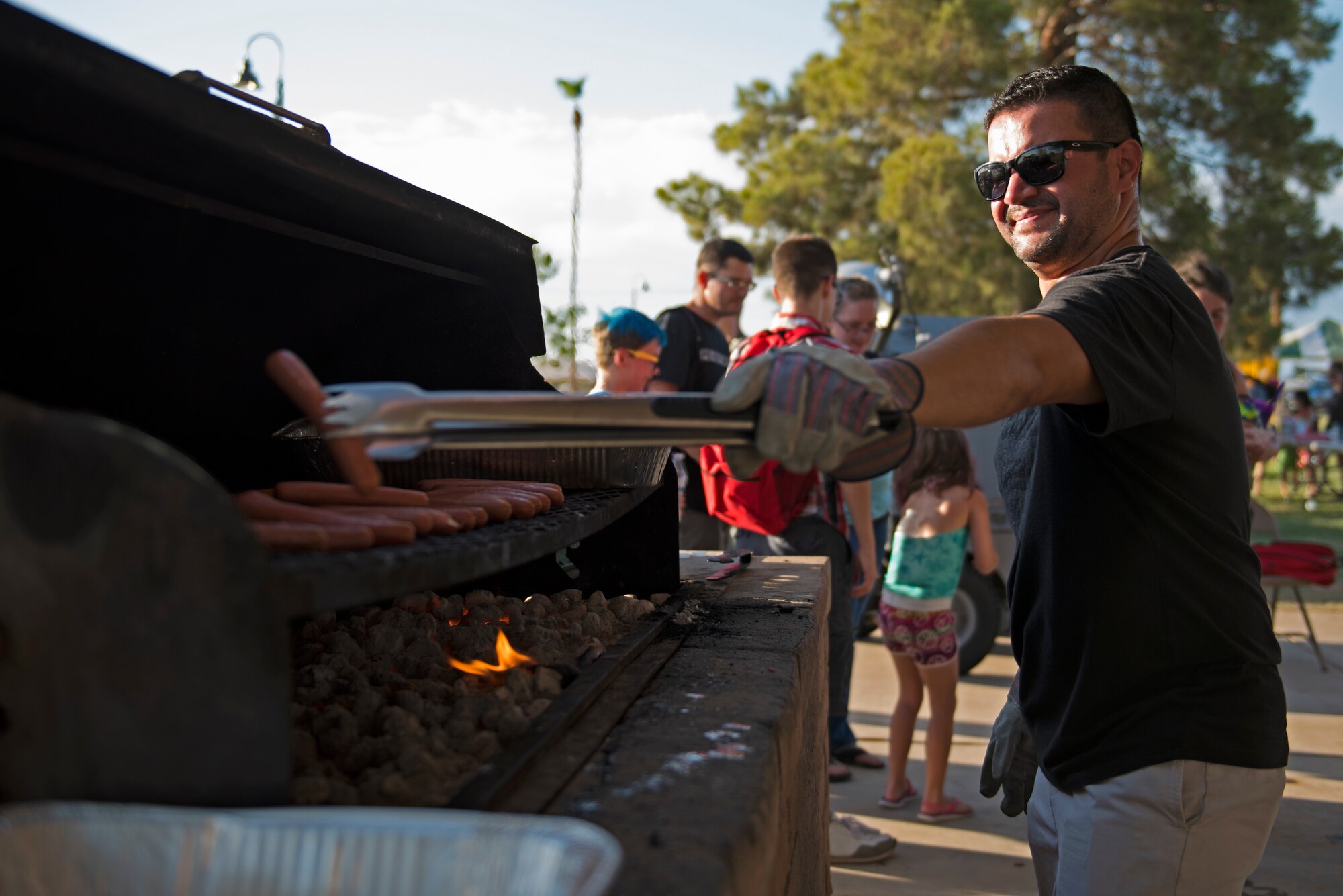 A volunteer cooks hotdogs for the Back-To-School Bash July 25, 2018, at Luke Air Force Base, Ariz. In addition to providing free school supplies to kids, the Bash offered families and attendees free food, games, and prize drawings. (U.S. Air Force photo by Senior Airman Ridge Shan)
