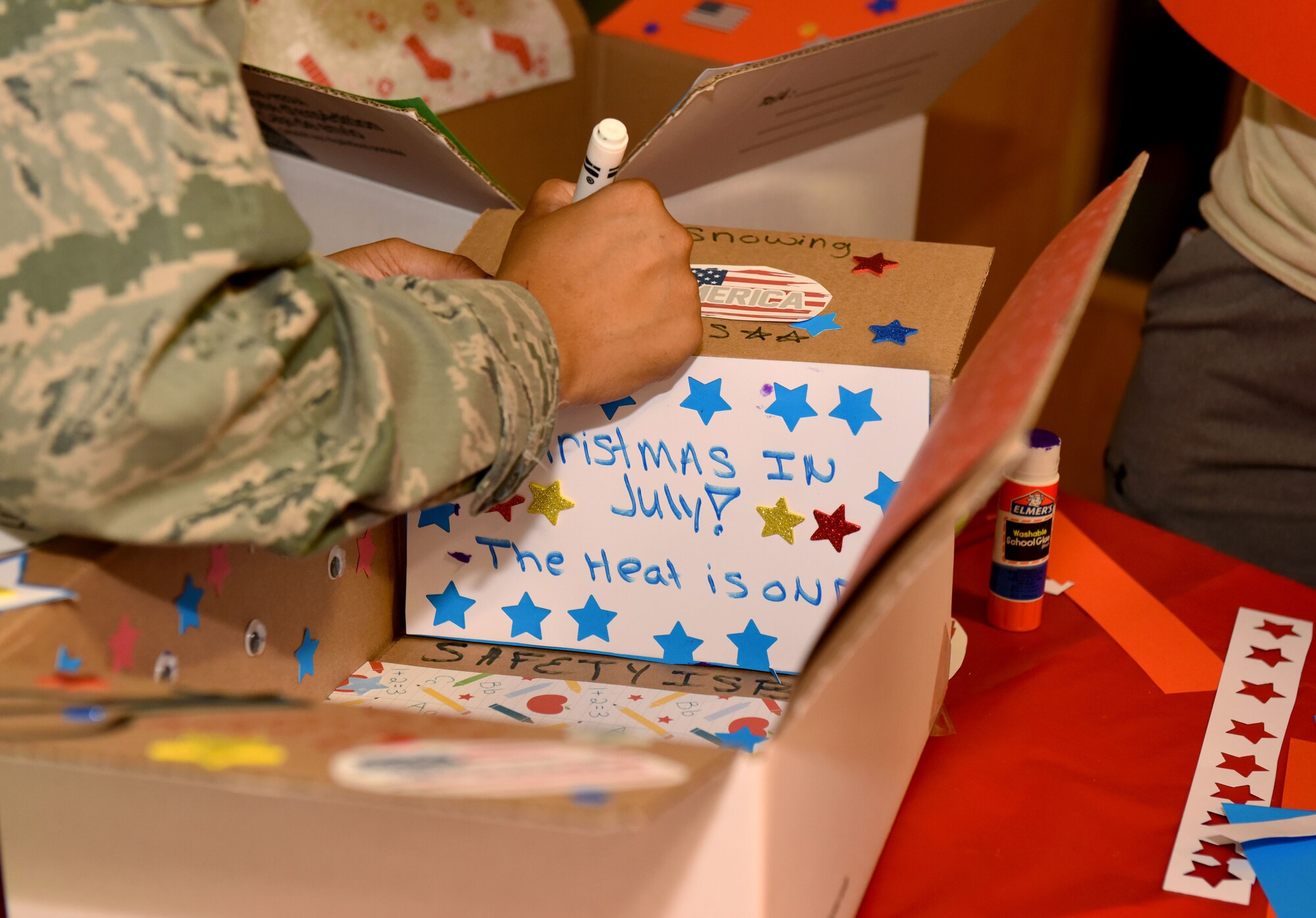 U.S. Air Force Staff Sgt. Brittany McGill, 100th Air Refueling Wing occupational safety craftsman, decorates a care package box for a deployed colleague at RAF Mildenhall, England, July 24, 2018. Each month, a different unit within the wing staff hosts and organizes the event. (US. Air Force photo by Senior Airman Lexie West)