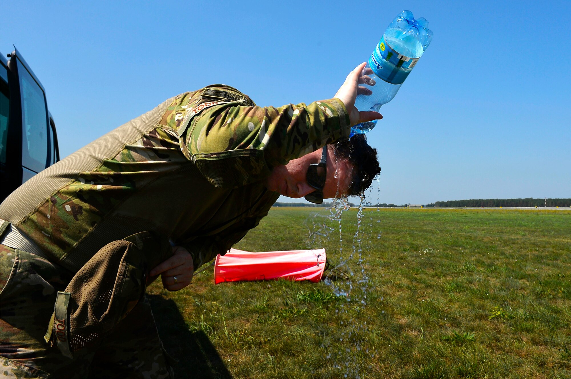 U.S. Air Force Tech. Sgt. Joshua Todd, 435th Contingency Response Group weather specialist, pours water over his head while waiting to survey the landing zone at Powidz Air Base, Poland, Aug. 1, 2018. Contingency response Airmen go out to a variety of austere and hostile environments to establish sites critical to mission accomplishment. (U.S. Air Force photo by Senior Airman Joshua Magbanua)