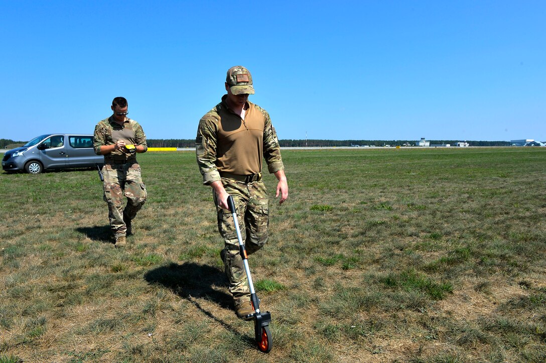U.S. Air Force Staff Sgt. Matthew Montgomery, front, and Tech. Sgt. Laramie Combs, both 435th Contingency Response Group contingency response air field managers, measure the distance at a landing zone on Powidz Air Base, Poland, Aug. 1, 2018. Contingency response airfield managers use a variety of tools to establish landing and drop zones in austere environments. (U.S. Air Force photo by Senior Airman Joshua Magbanua)
