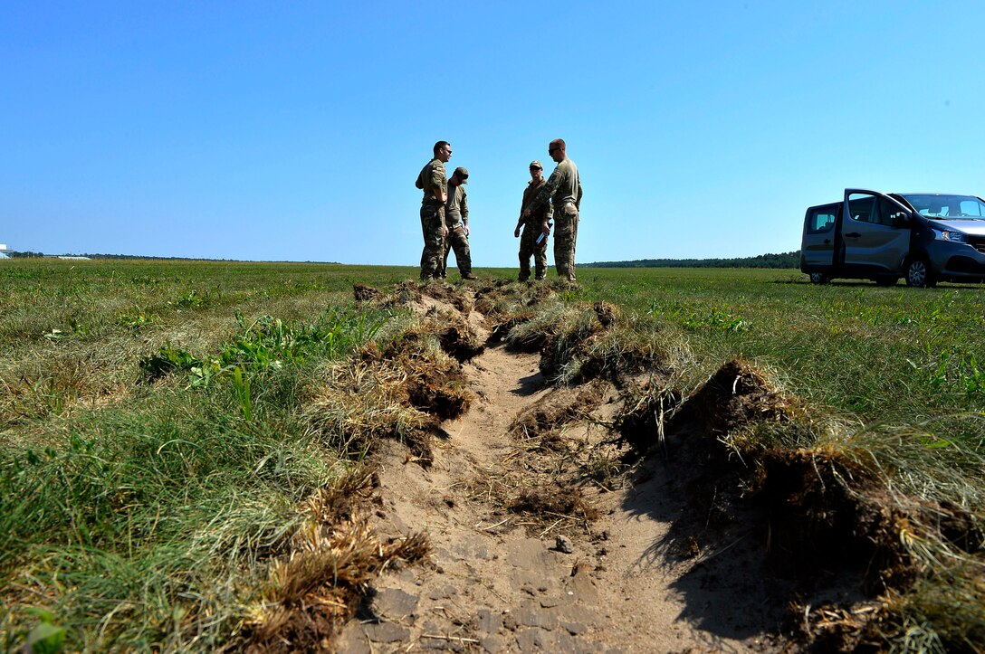 U.S. Airmen assigned to the 435th Contingency Response Group assess a rut generated by an aircraft that landed on Powidz Air Base, Poland, Aug. 1, 2018. Landing zone establishment crews conduct site surveys, assessments, and construction of dirt runways and airdrop targets in a variety of austere environments. (U.S. Air Force photo by Senior Airman Joshua Magbanua)